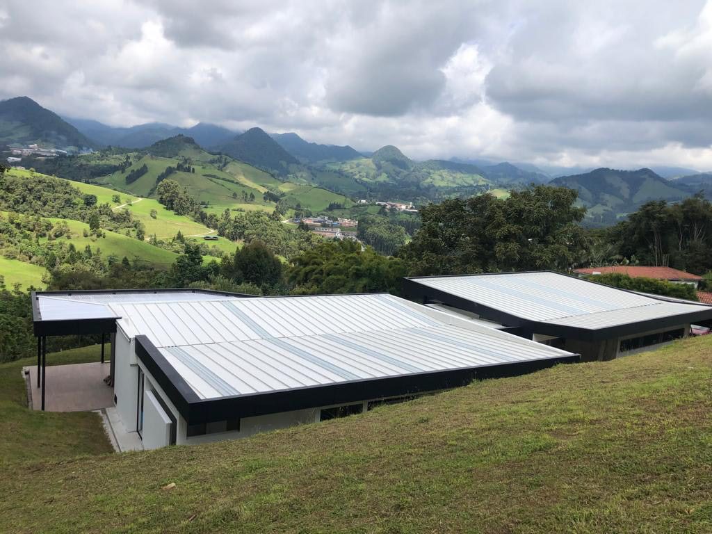 Dos casas con cubierta metálica continua sobre el paisaje de montaña